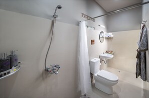 A modern bathroom with a shower, toilet, sink, and towel rack.