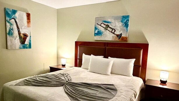A hotel room with a large bed, two bedside tables with lamps, and two paintings on the walls.