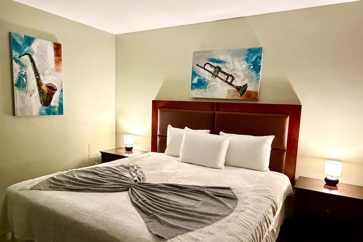 A hotel room with a large bed, two bedside tables with lamps, and two paintings on the walls.