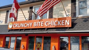 A restaurant named 'CRUNCHY BITE CHICKEN' with a red and white exterior, American and Canadian flags, and a chicken logo.