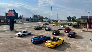 A parking lot with various cars, including a yellow Mustang convertible, and a sign that reads "ROCKY RIVER".