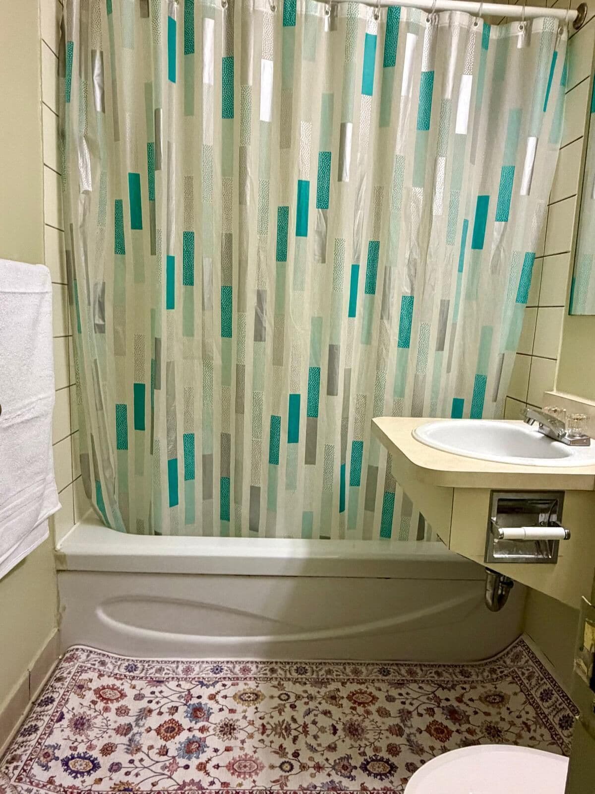 Een badkamer met een bad, een wastafel en een vloer met een patroon.