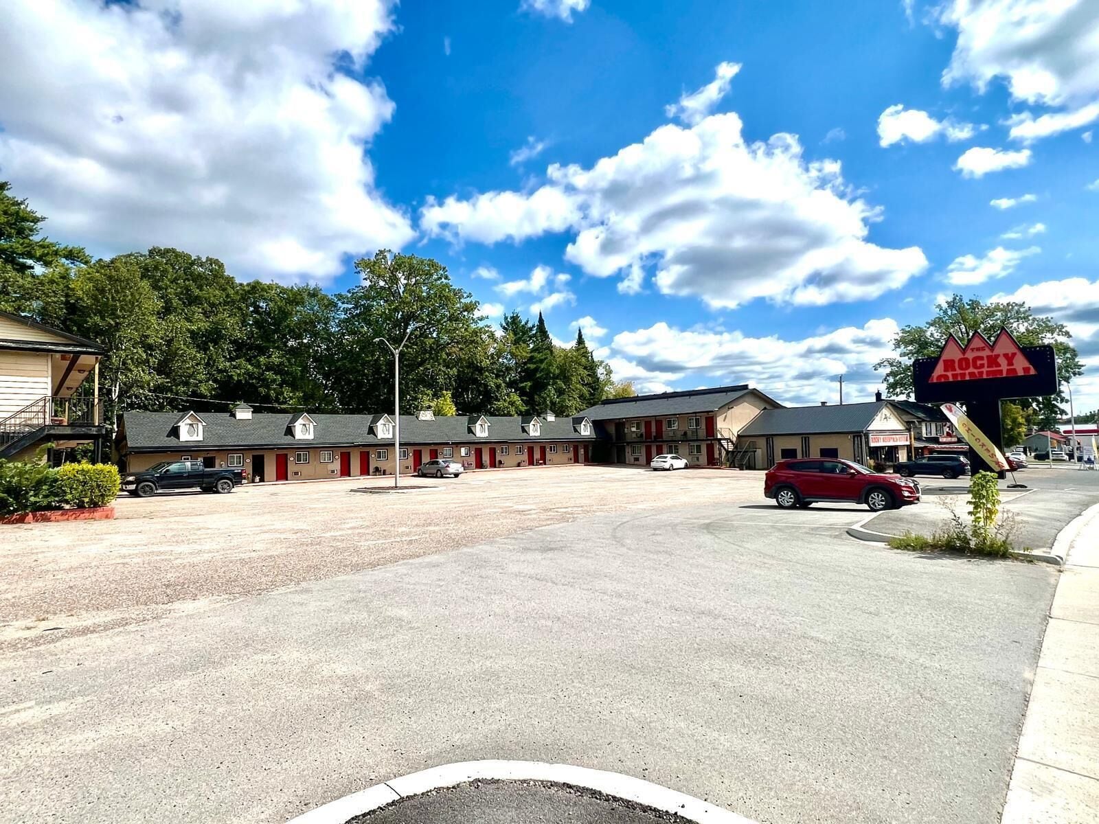 Un motel con varias habitaciones, un estacionamiento y un letrero que dice 'The Rocky Mountain Inn'.