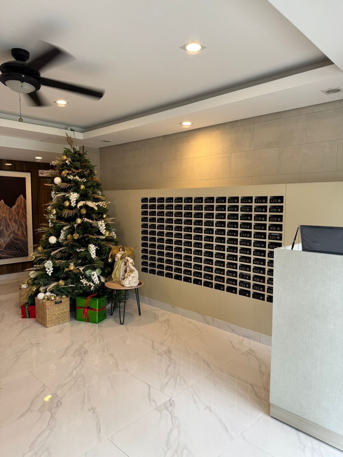 Un vestíbulo moderno con un árbol de Navidad, una mesa de recepción y una pared con números de habitación.