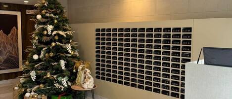 Un vestíbulo moderno con un árbol de Navidad, una mesa de recepción y una pared con números de habitación.