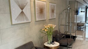 A modern lobby with a seating area, a vase with flowers, and three abstract wall art pieces. - Cozy, Spacious 1-bedroom Condo in Novaliches, Perfect for Staycations & Creators (Quezon City)