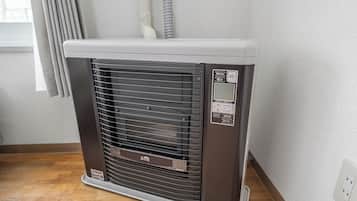 Een draagbare verwarming met een bedieningspaneel, geplaatst op een houten vloer tegen een muur.