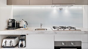 A modern kitchen with a gas stove, coffee maker, toaster, and blender. - One-Bed Apartment Close to Cafés and Coast (Port Melbourne)