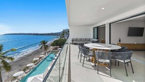 Un balcon avec une piscine, un coin repas avec des chaises et un téléviseur.