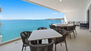 Un balcón con vista al mar, una mesa redonda y dos sofás.