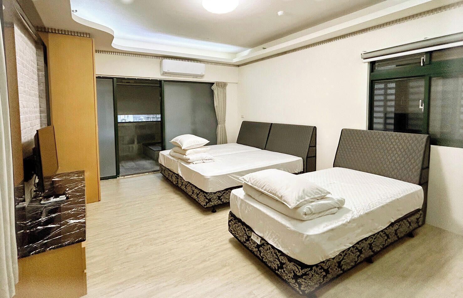 A hotel room with two beds, a desk, and a window.