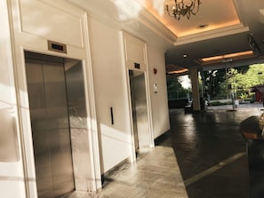 A hallway with three elevators and a chandelier. - Stallions Suite Penang (George Town)