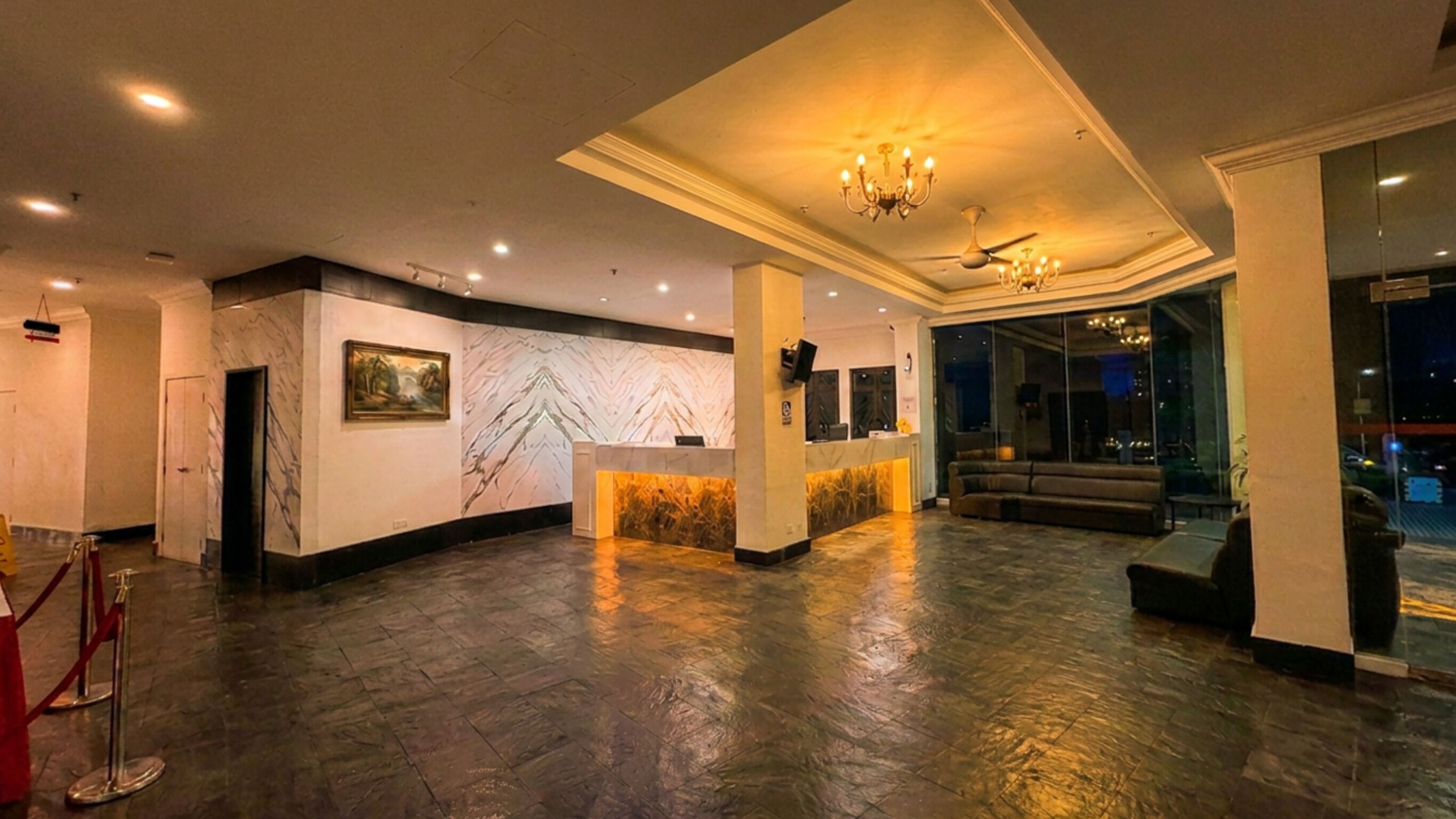 A hotel lobby with a reception desk, seating area, and artwork on the walls.