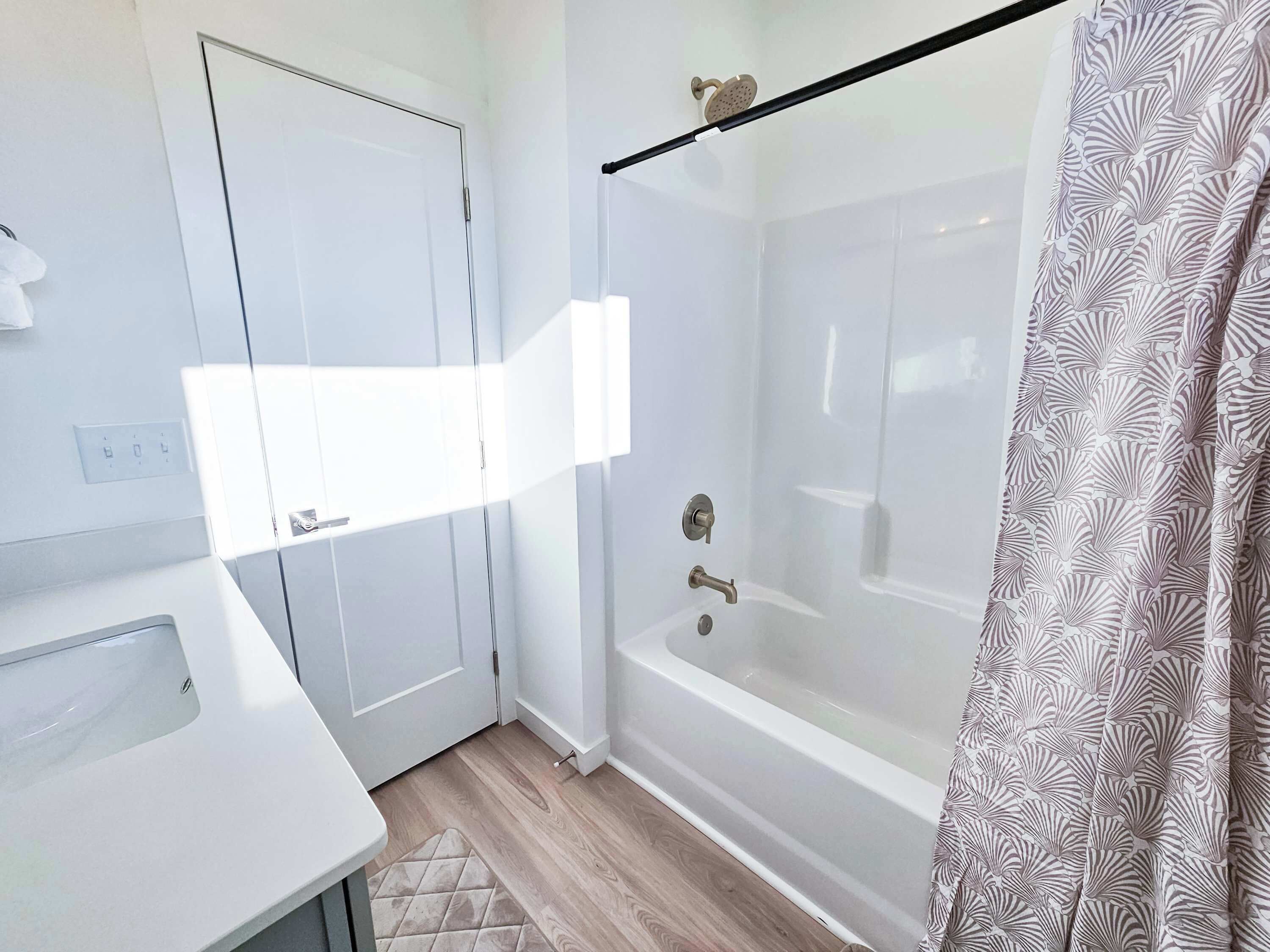 A modern bathroom with a white shower, a bathtub, and a toilet.