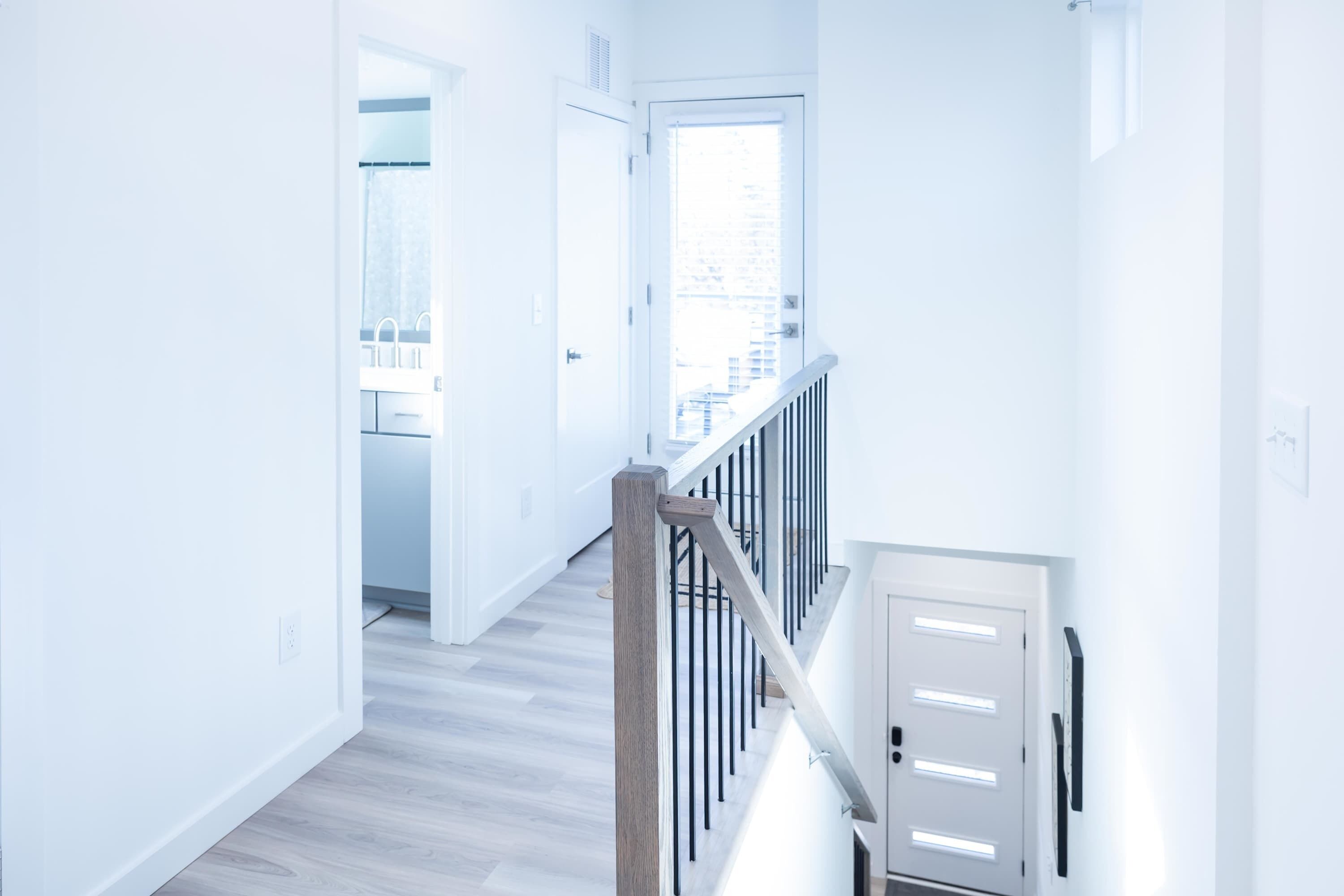 Un corridoio moderno e luminoso con una scala in legno e vista sulla città attraverso un'ampia finestra.