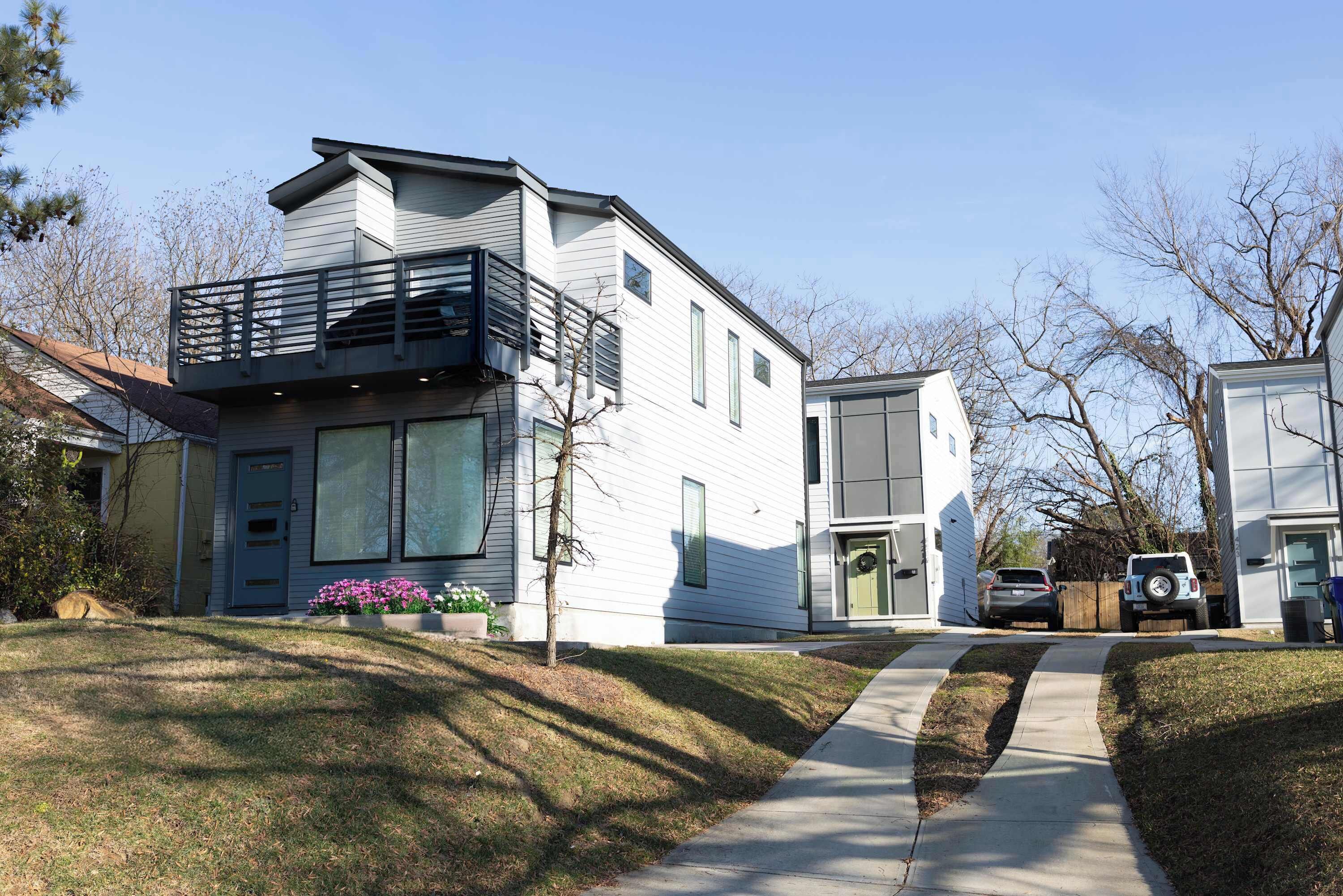 Une maison moderne à deux étages, dotée d’un balcon, d’un garage et d’une allée.