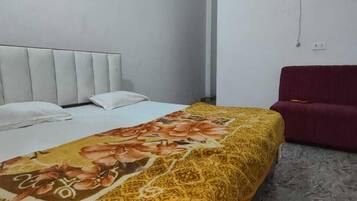 Una habitación de hotel con una cama, un sofá rojo y un equipo de aire acondicionado en la pared.