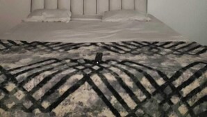 A bedroom with a bed, two windows, and a headboard. - Shubh Hotel (Phulpur)