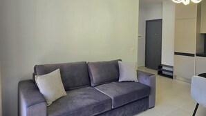 En moderne stue med en grå sofa, to puder og en tidssvarende lampe.