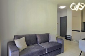 Ein modernes Wohnzimmer mit einem grauen Sofa, zwei Kissen und einer zeitgemäßen Leuchte.