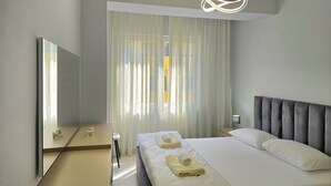 Et moderne hotelværelse med en stor seng, et sengebord, et spejl og lette gardiner.