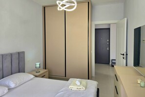 A hotel room with a bed, bedside table, lamp, and a wardrobe. - Happy Stay Apartment by the Sea 093 (Golem)