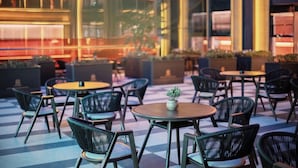 An outdoor seating area with round tables and chairs, potted plants, and a checkered floor pattern. - Power Stone Hotel Chengdu Kuanzhai Alley Branch (Chengdu)