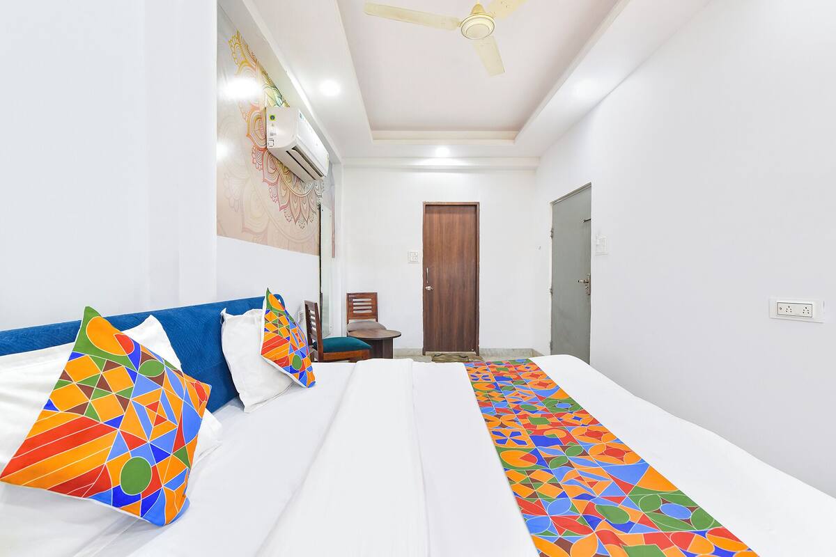 Una habitación de hotel con cama, escritorio, silla, armario y ventilador de techo.