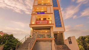A multi-story hotel with a modern design, featuring a staircase leading to the entrance, and signage for 'Hotel Dwarka Inn & Restaurant'. - Fabhotel Dwarika Inn (Varanasi)