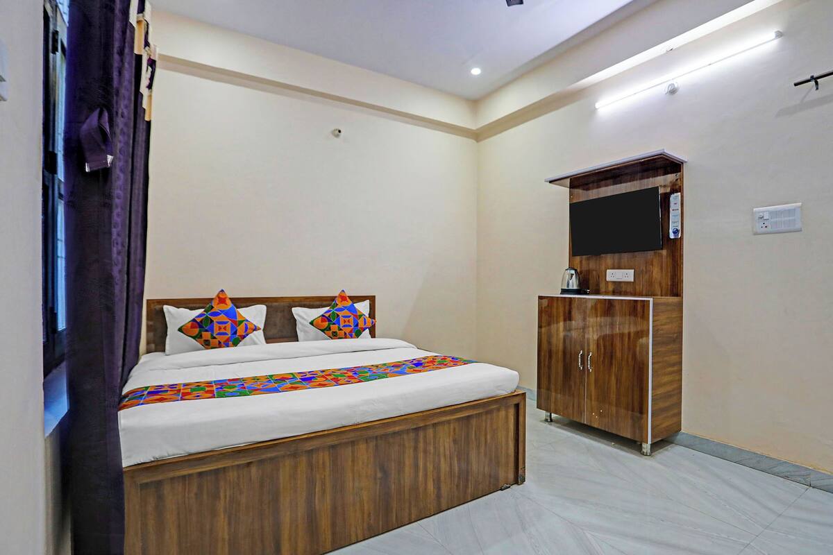 A bedroom with a wooden bed, a wardrobe, and a flat-screen TV on the wall.
