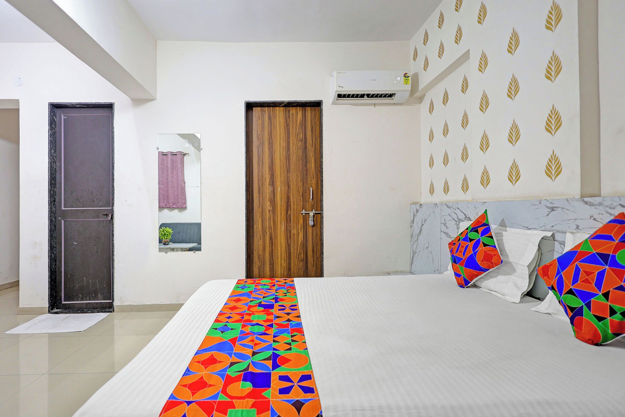 A bedroom with a bed, a wooden door, an air conditioner, and a patterned wall.