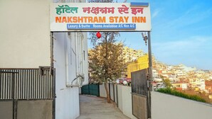 L’entrée d’un hôtel, avec une enseigne indiquant « NAKSHATRAM STAY INN » et précisant : « Chambres de luxe et suites disponibles, avec ou sans climatisation ».