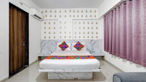 Une chambre à coucher avec une tête de lit en marbre, un lit agrémenté de coussins géométriques aux couleurs vives, une porte en bois et un rideau violet.