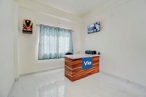 A reception desk with a 'Via' sign, a window with patterned curtains, and a wall-mounted picture. - Via Wisdom (Rajgurunagar)
