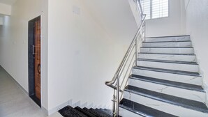 A staircase with a metal handrail and marble steps, leading to a landing with a small window. - Via Wisdom (Rajgurunagar)