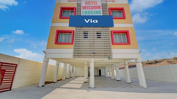 A multi-story hotel named 'Hotel Wisdom Lodging' with a central staircase and a covered walkway. - Via Wisdom (Rajgurunagar)