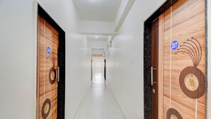 A hallway with two wooden doors, each marked with a number. The hallway has a tiled floor and white walls. - Via Wisdom (Rajgurunagar)