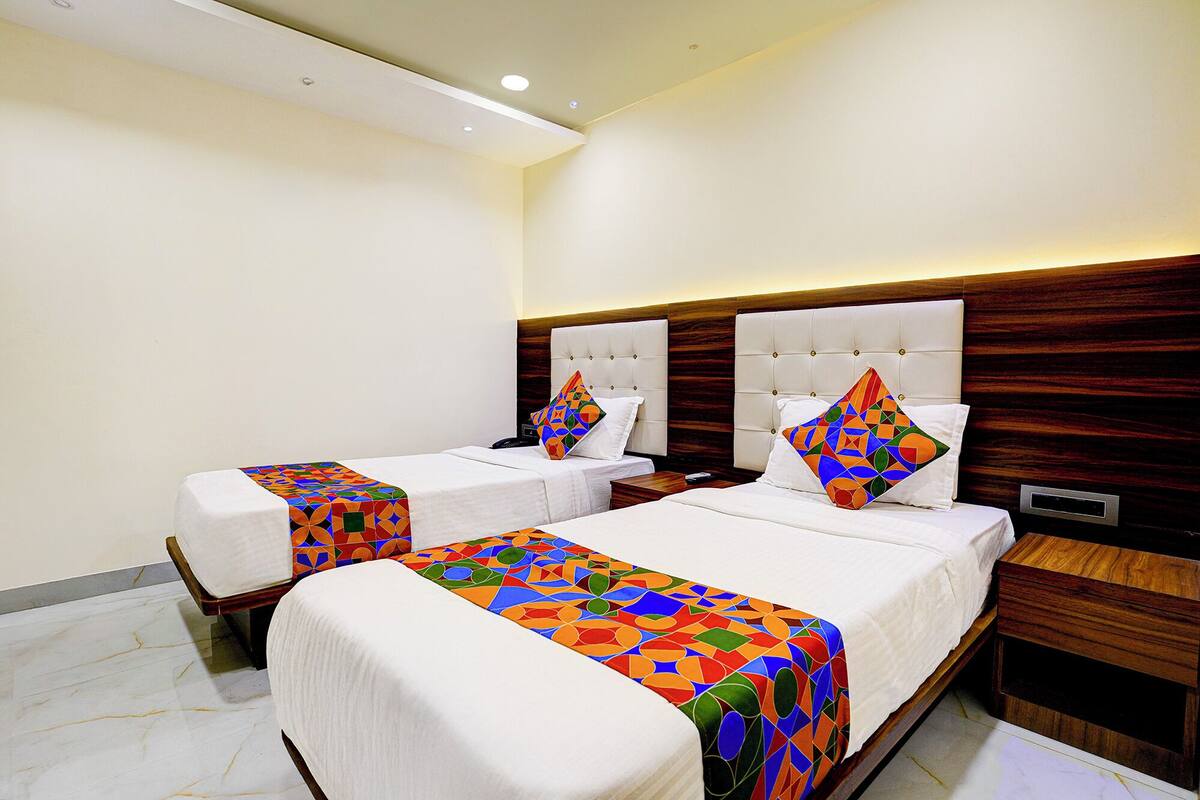 A hotel room with two beds, each with a colorful geometric-patterned bedspread.