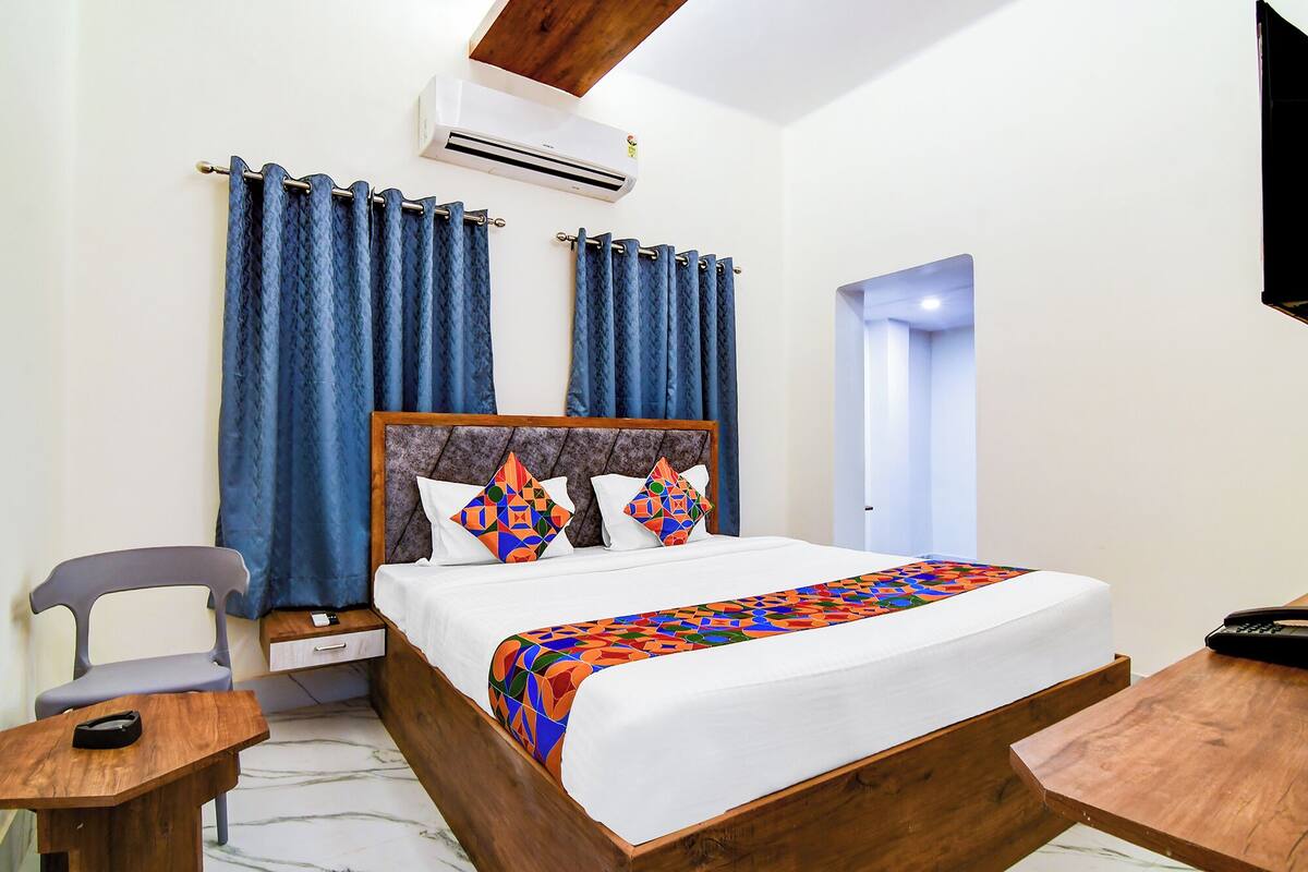 A hotel room with a wooden bed, a desk, a chair, and a nightstand.
