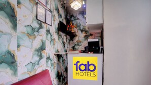 A reception area with a marble wall, a red sofa, and a sign for 'fab hotels'. - Via Saini Residency (Mumbai)