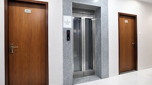 A hallway with three wooden doors, each marked with a number. - FabHotel Kamari Inn, Vijay Nagar (Indore)