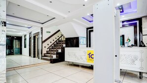 A modern lobby with a staircase, a reception desk, and a clear exit sign. - Fabhotel Shivdev International (New Delhi)