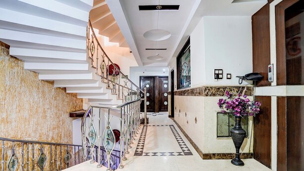 A modern hotel lobby with a marble staircase, a reception desk, and a decorative vase. - Fabhotel Shivdev International (New Delhi)
