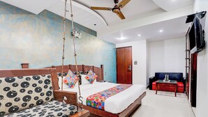 A modern bedroom with a bed, a sofa, a ceiling fan, and a TV. - Fabhotel Shivdev International (New Delhi)