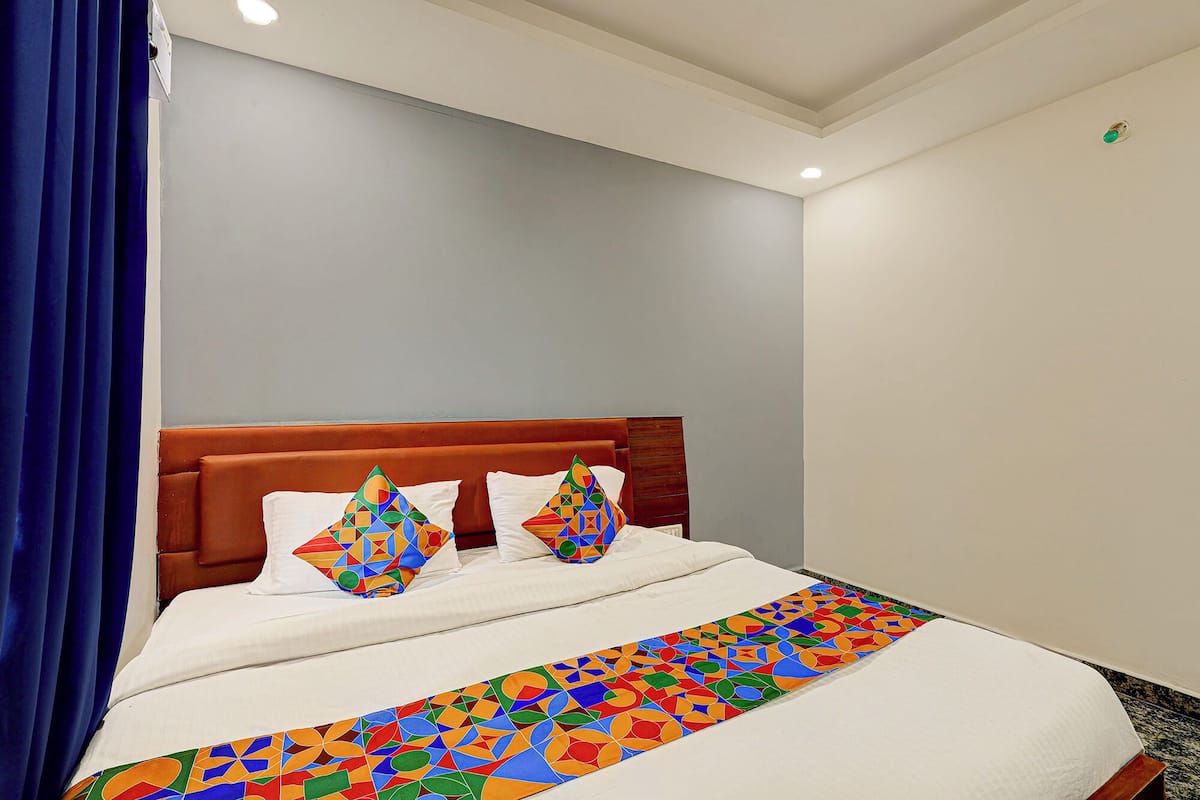 Une chambre d’hôtel avec un lit, des rideaux bleus et une couvre-lit à motifs.