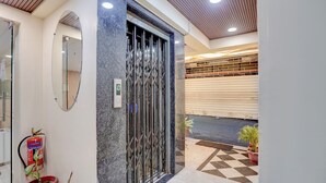 A modern entrance with a glass door, a digital display, and a fire extinguisher. - Fabhotel Aliza (Kolkata)