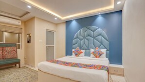 A modern bedroom with a large bed, a headboard with a geometric design, and a blue accent wall. - Fabhotel Aliza (Kolkata)