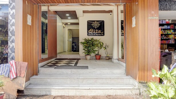 A hotel entrance with a wooden facade, a sign reading "Aliza Hotel & Banquet", and potted plants at the steps. - Fabhotel Aliza (Kolkata)