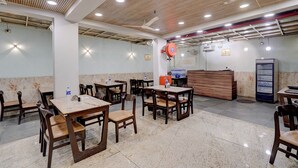 A restaurant with wooden ceiling panels, tables, and chairs. - Fabhotel Aliza (Kolkata)