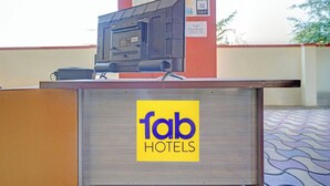 A reception desk with a 'fab hotels' sign, a red pillar, and a tiled floor. - Via Comfort Hub (Hingna)